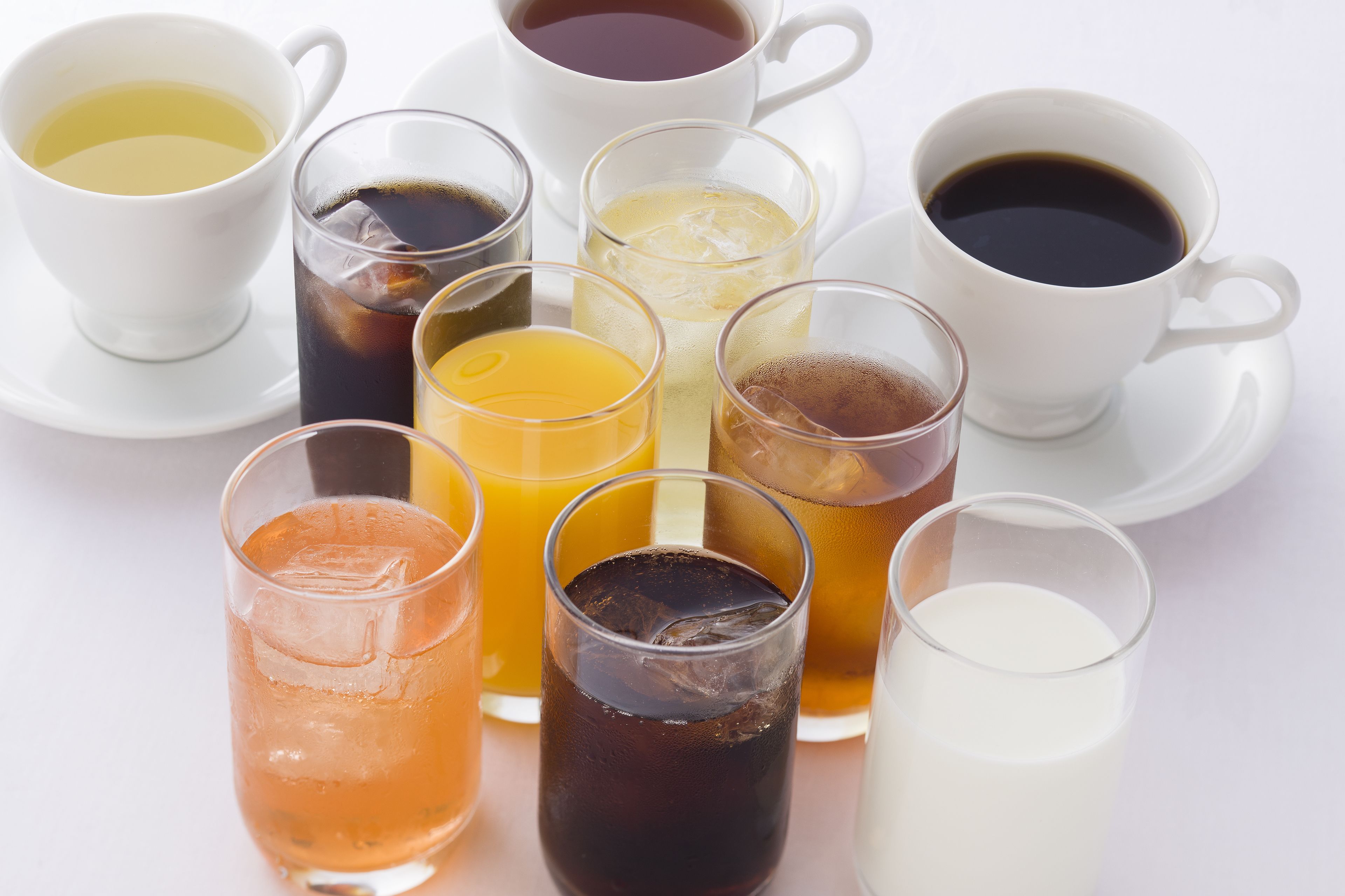 Variedad de bebidas como café, té y jugo, servidas en distintos vasos y tazas.