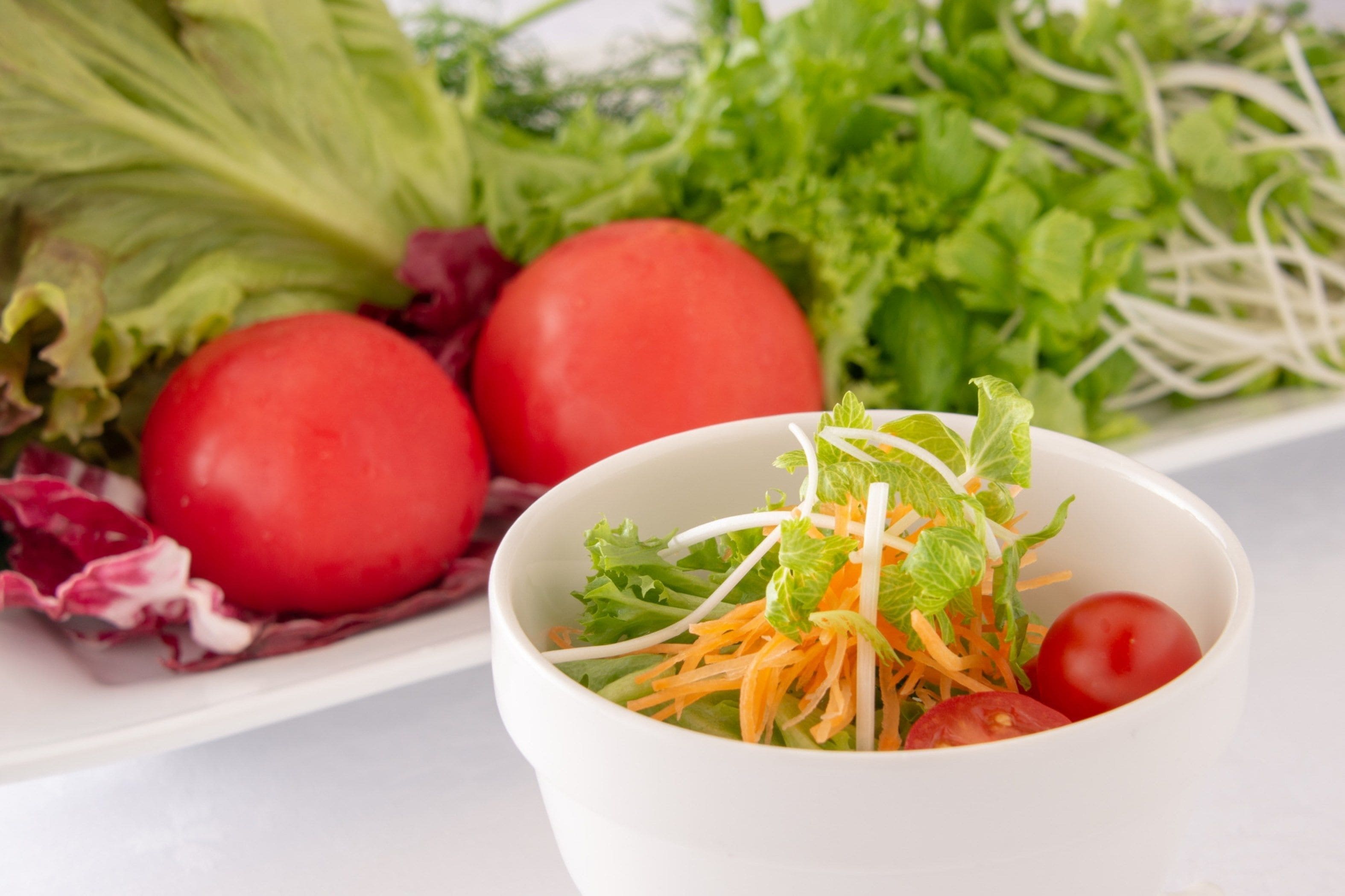Une salade composée de laitue, de carottes et de tomates.