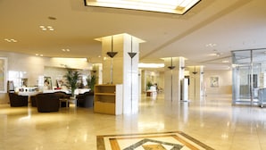 A spacious lobby with a reception desk, seating area, and a decorative floor pattern.