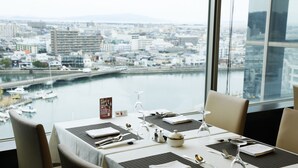 A dining table set with a view of a cityscape and a body of water.