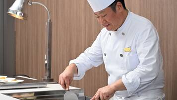 A chef in a white uniform preparing food on a grill.