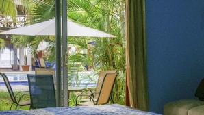 Una habitación con cama, vista a una piscina y palmeras.
