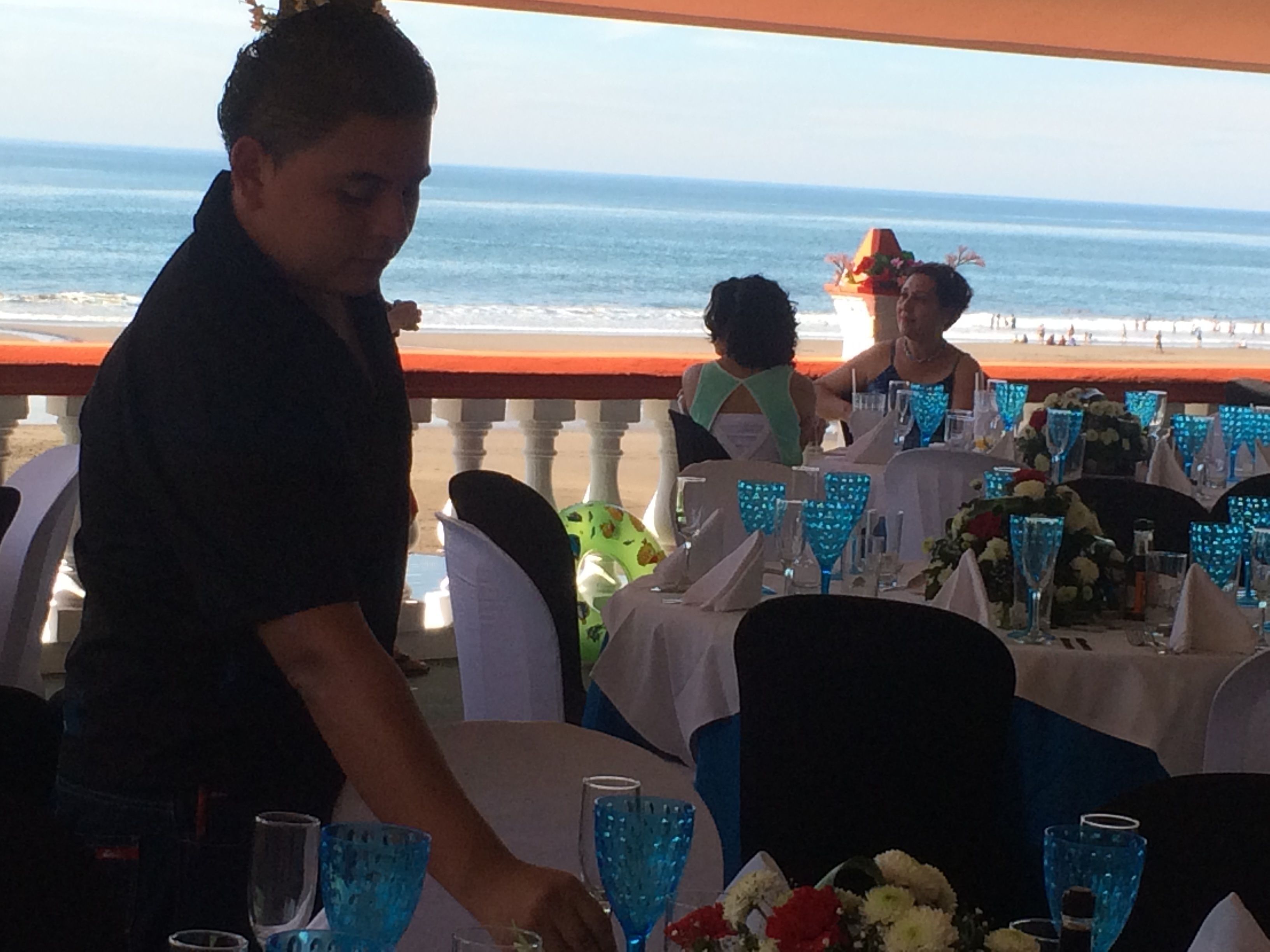 Un restaurante con mesas dispuestas para una comida, con vista a la playa.