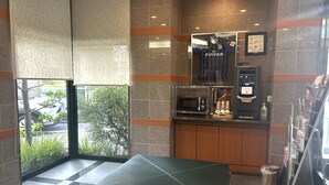 A modern hotel lobby with a seating area, a coffee machine, and a view of the outside. - Hotel Route Inn Oita Ekimae (Oita)