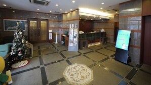 A lobby with a reception desk, a Christmas tree, and a digital screen. - Hotel Route Inn Oita Ekimae (Oita)
