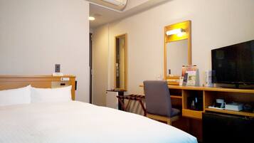 A hotel room with a bed, a desk with a chair, a television, and a mirror.