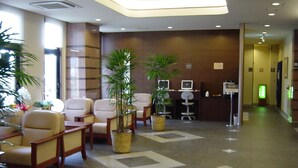 Eine Lobby mit Sitzgelegenheiten, Topfpflanzen, einem Empfangstresen und einem Computerarbeitsplatz.