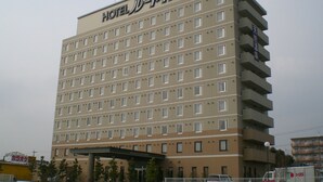 Ein mehrstöckiges Hotel mit einheitlicher Fassade, zahlreichen Fenstern und einer flachen Dachfläche.