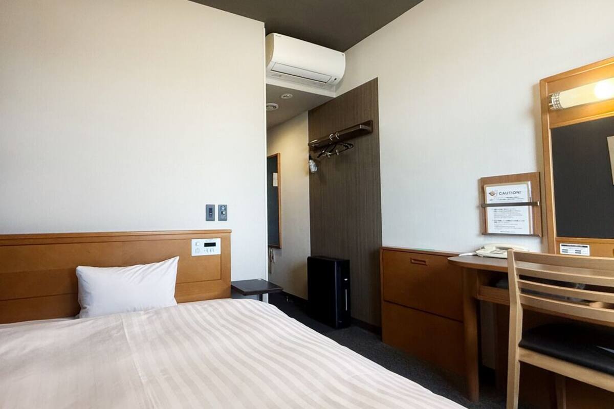 Une chambre d’hôtel équipée d’un lit, d’un bureau, d’une chaise et d’un miroir.