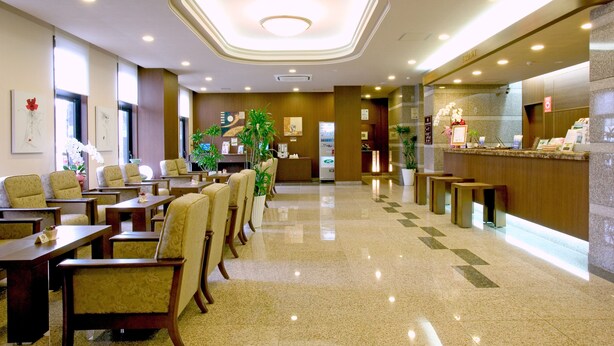 A hotel lobby with a reception desk, seating area, and decorative plants. - Hotel Route Inn Yatsushiro (Yatsushiro)