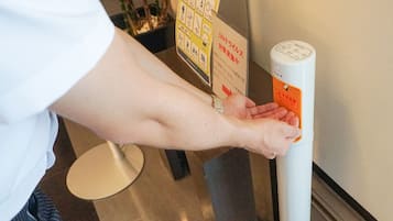 A person using a hand sanitizer dispenser.