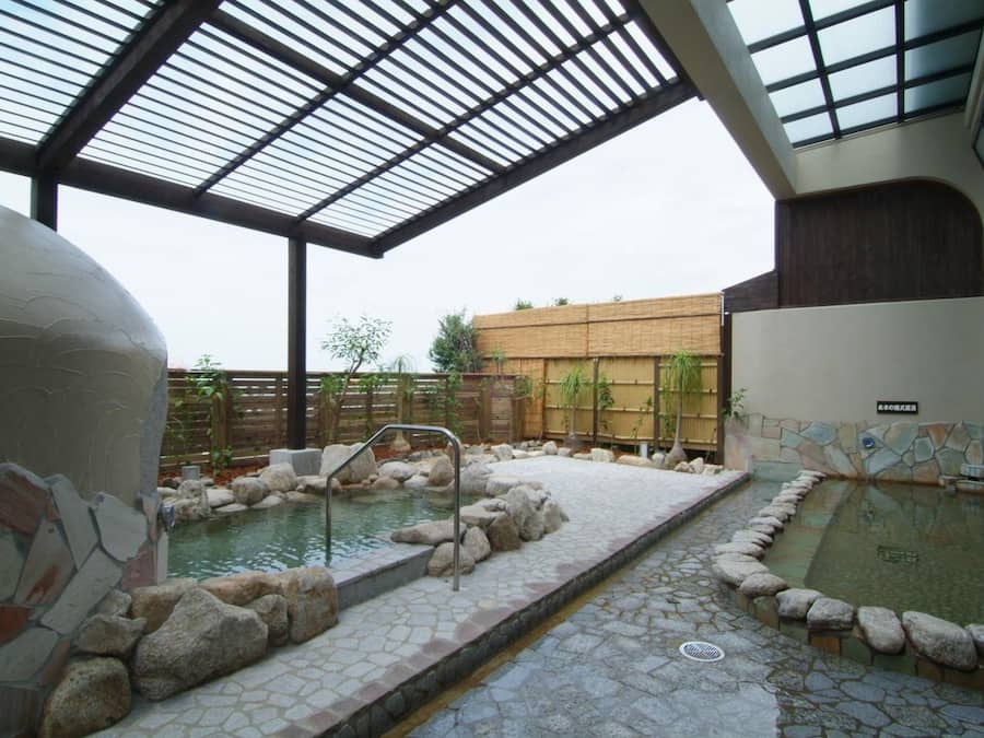 A spa area with a pool, stone tiles, and a wooden fence.