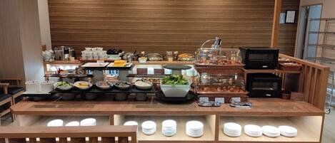 A buffet setup with various food items and a coffee machine.