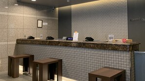 Un espace d’accueil doté d’un comptoir en marbre, d’une horloge et d’un panneau indiquant l’emplacement de la réception.