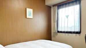 A hotel room with a large bed, a framed picture on the wall, and a window with curtains. - Hotel Route-Inn Court Kofu (Kofu)
