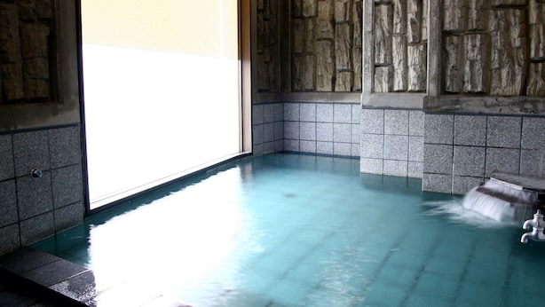A stone-walled room with a blue-tiled floor and a small waterfall feature. - Hotel Route-Inn Court Kofu (Kofu)