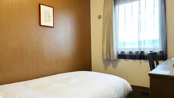 A hotel room with a bed, a desk, and a window with curtains.