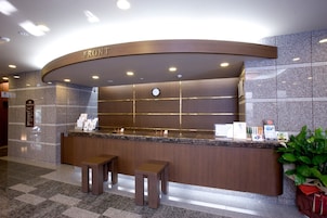 A reception desk with a clock, a sign reading "FRONT", and a plant to the right.