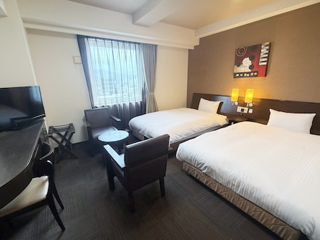 A hotel room with two beds, a desk, a chair, a small table, a TV, and a window with curtains.. Hotel Route Inn Nobeoka Ekimae