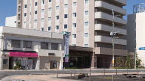 Un hotel de varios pisos con un letrero verde en la parte superior y otro más pequeño en la lateral.