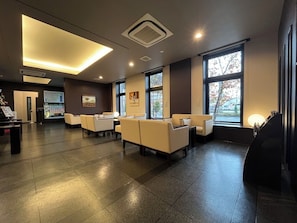 A modern lobby with seating, large windows, and a vending machine.