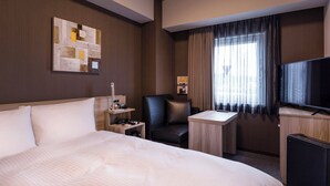 Une chambre d’hôtel avec un grand lit, un bureau, une chaise, une télévision et une fenêtre avec des rideaux.