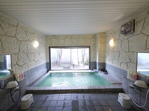 A stone-walled bathroom with a large window, a bathtub, and a shower area. - Hotel Route-Inn Court Yamanashi (Yamanashi)