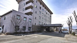 Un hôtel à plusieurs étages, doté d’une façade sobre, d’une entrée couverte et d’un parking.