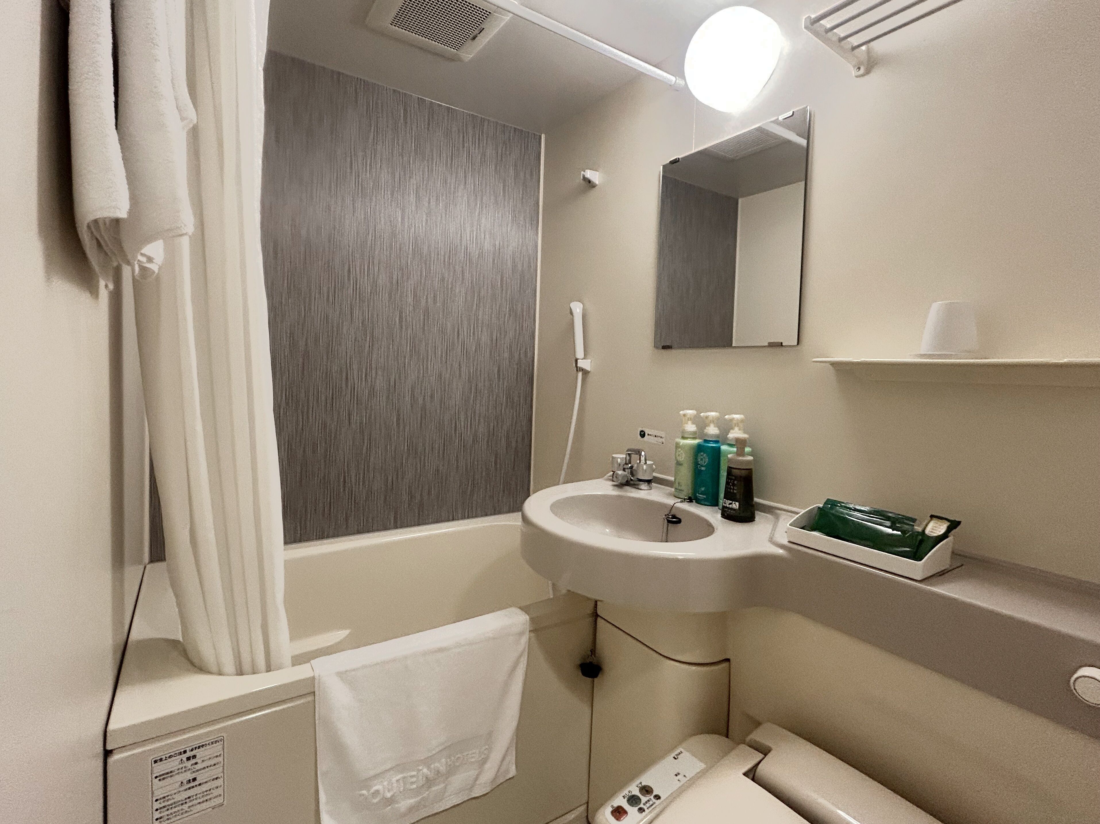 Un baño con bañera, lavabo, espejo y artículos de aseo.