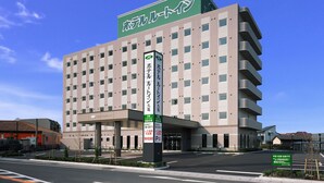 Un hotel de varios pisos con un llamativo letrero verde en la parte superior.