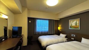 Habitación de hotel con dos camas, un escritorio con televisor, una ventana con cortinas y un cuadro en la pared.