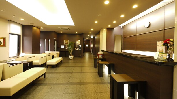 A hotel lobby with seating areas, a reception desk, and a large mirror.