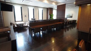 Un restaurant moderne doté d’une longue table conviviale, de banquettes et d’un téléviseur à écran plat fixé au mur.