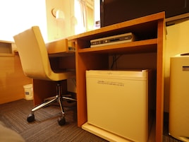 Um espaço de escritório compacto com mesa, cadeira e um pequeno frigorífico.