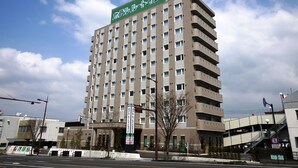 Un hôtel à plusieurs étages, reconnaissable à son grand panneau vert situé en haut de l’immeuble.