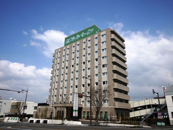 A multi-story hotel with a prominent green sign on the top.
