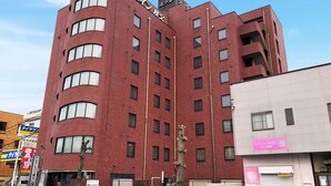A multi-story red brick building with a modern design, featuring a mix of rectangular and arched windows. - Hotel Route-Inn Seibu Chichibu Ekimae (Chichibu)