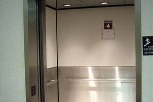 Interior de un ascensor con acabado metálico, un cartel que indica el piso 4 y un símbolo de accesibilidad para sillas de ruedas.