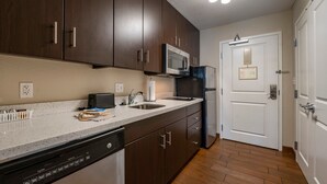 Una cocina moderna con armarios de madera oscura, un microondas de acero inoxidable y un lavavajillas.