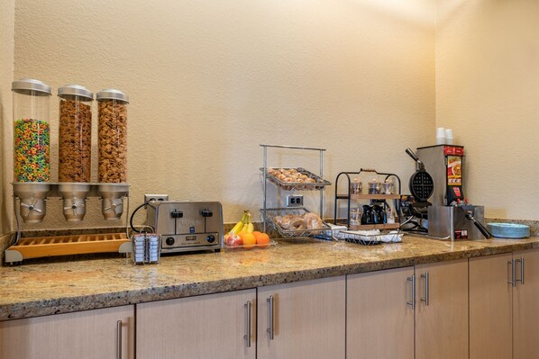 Una barra de desayuno con cereales, frutas y bollería.