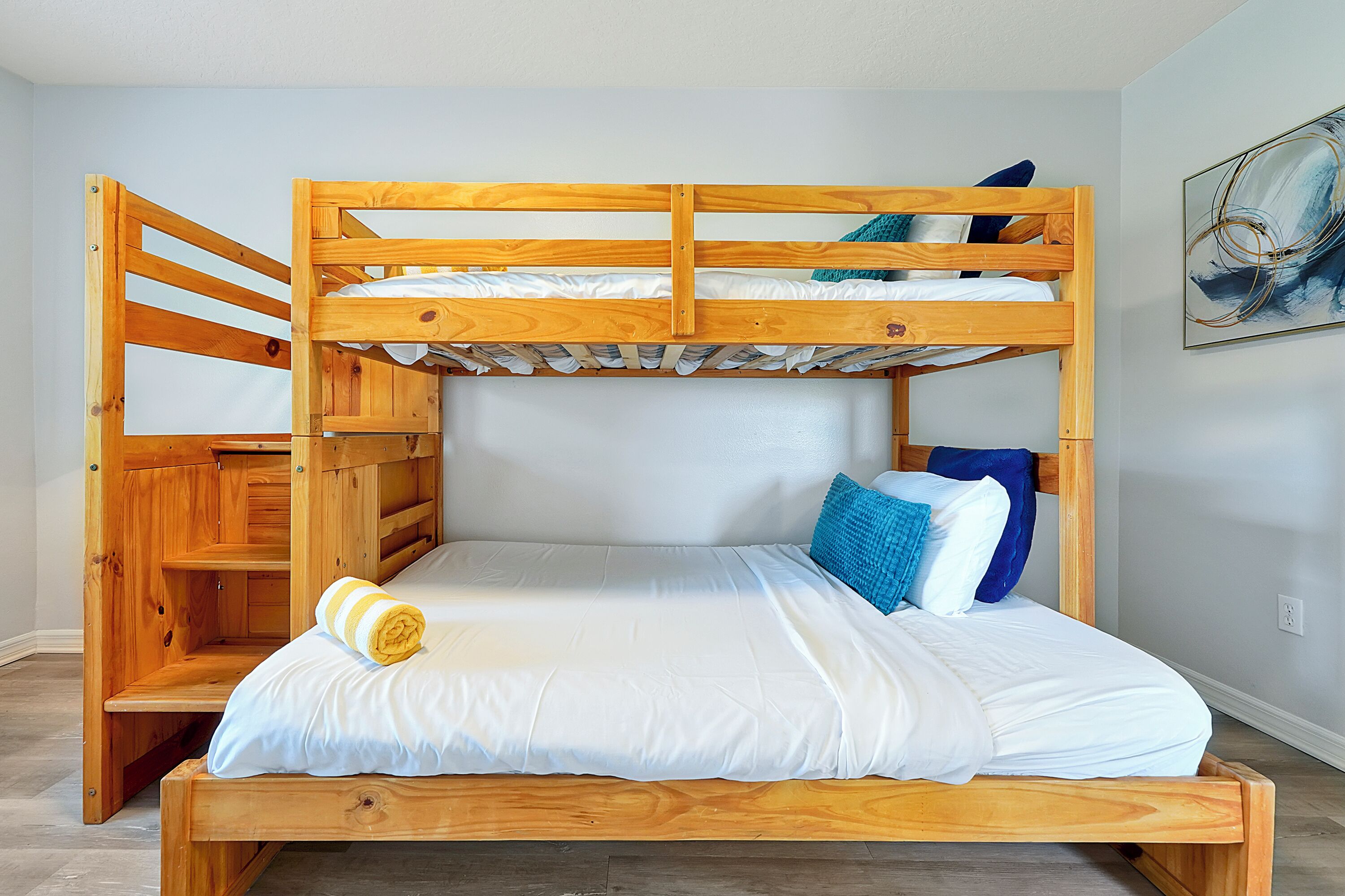A bunk bed with a wooden frame, white bedding, and a blue pillow.