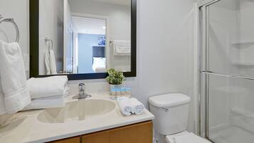 Un baño con lavamanos, espejo, inodoro y cabina de ducha de vidrio.