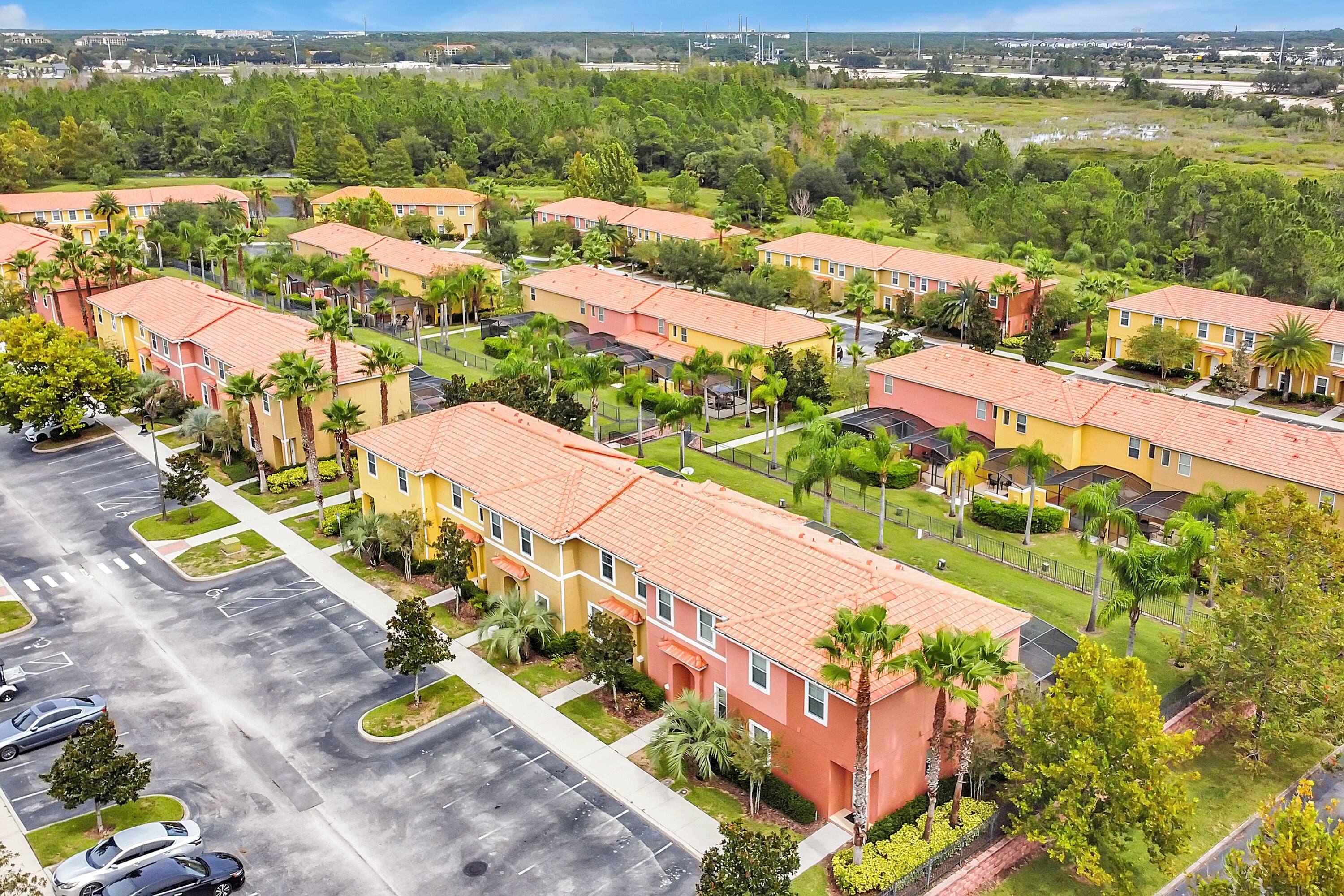 A residential complex with multiple two-story buildings, a parking lot, and surrounding greenery.
