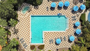 Vista aèria d'una zona de piscina amb paviment d'escacs, gandules i ombrelles.