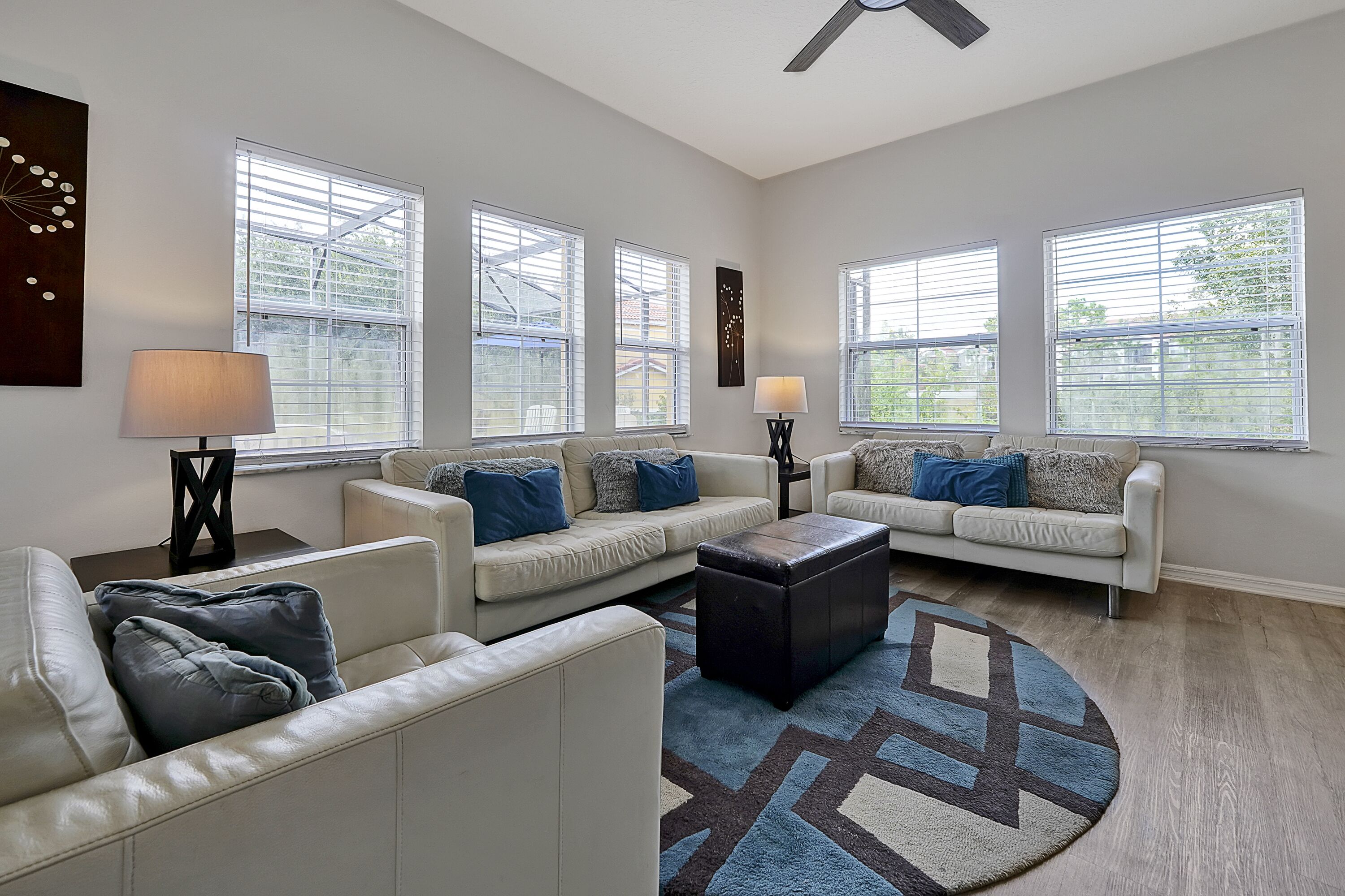 A spacious living room with two white sofas, a coffee table, and a patterned rug.