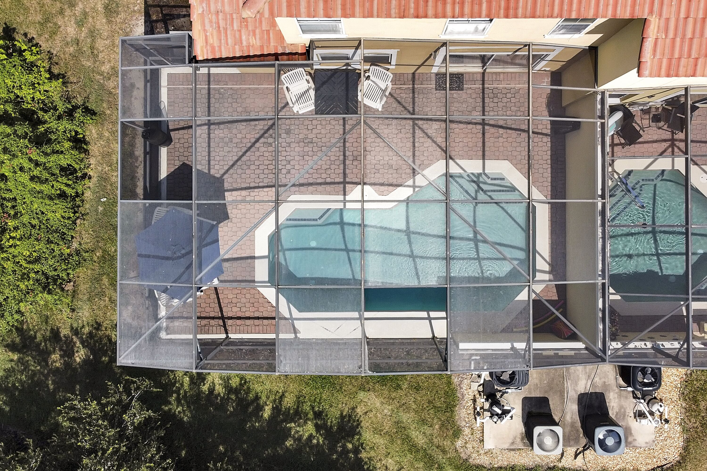 Vue aérienne d’une piscine sur le toit, dotée de parois en verre et entourée d’une structure métallique.