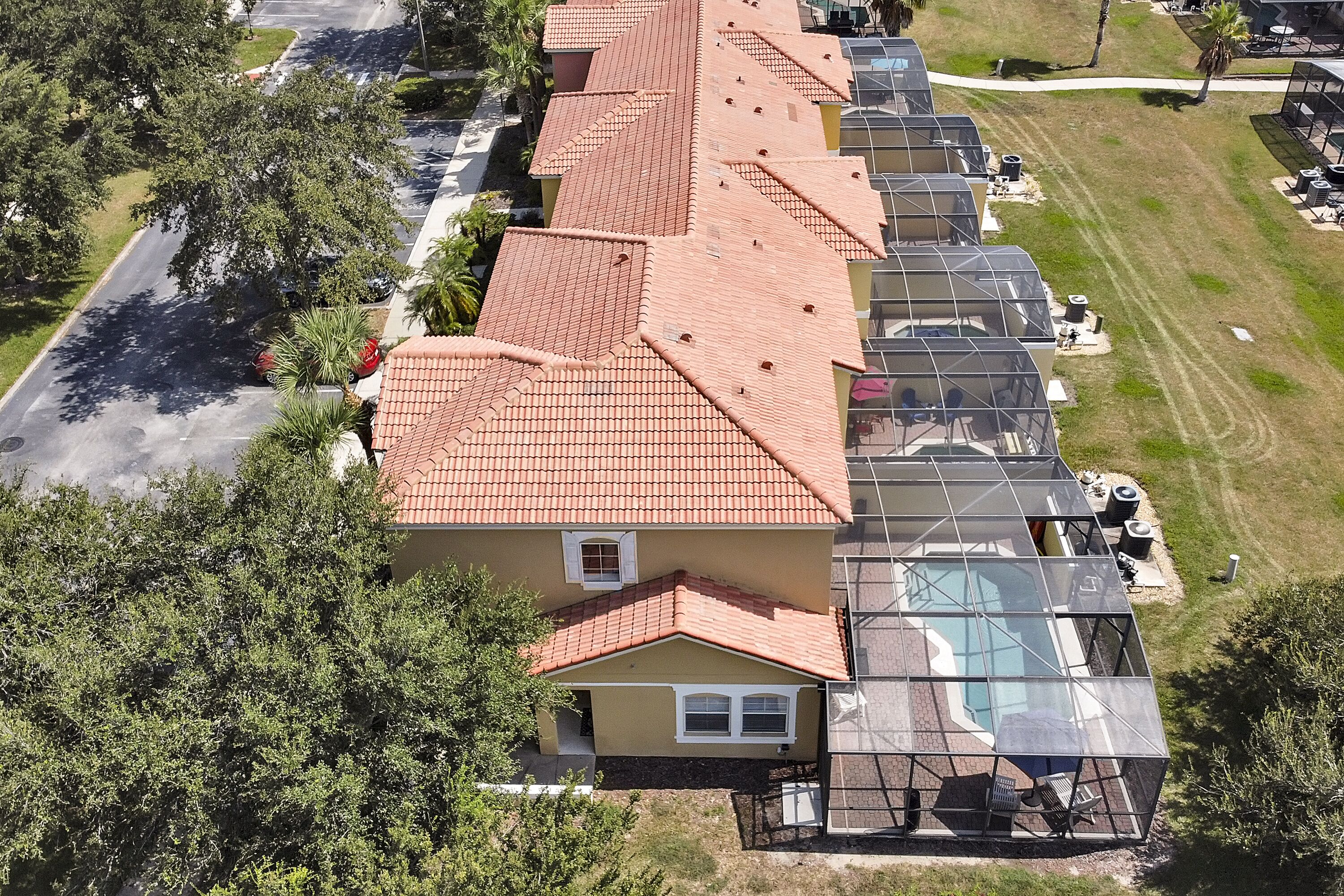 A row of houses with red-tiled roofs and a glass-enclosed swimming pool.