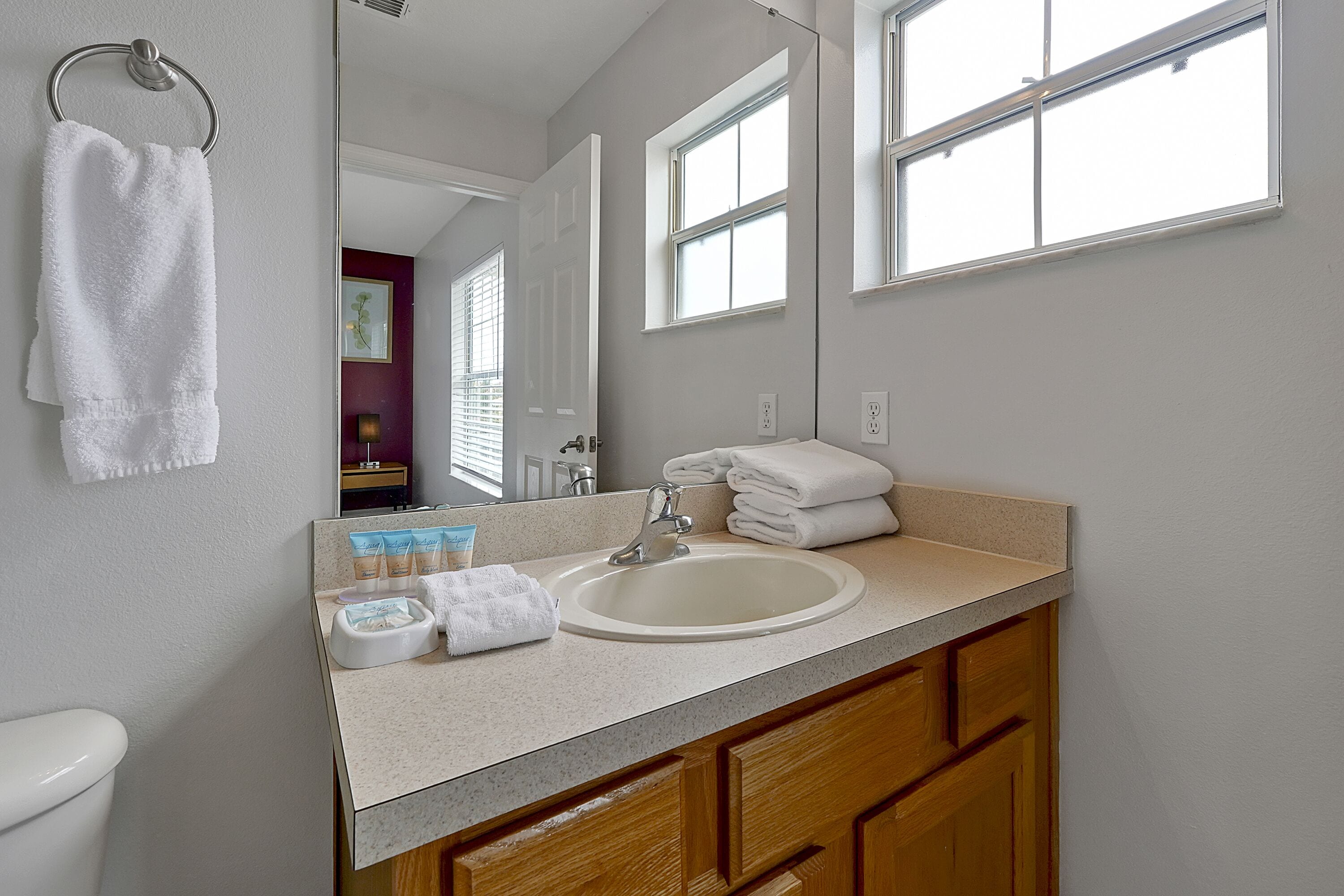 A bathroom with a sink, mirror, and towel rack.