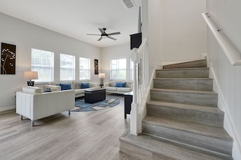 A modern living room with a grey sofa, a wooden coffee table, and a cityscape painting on the wall. at Encantada Resort Vacation Townhomes by IDILIQ