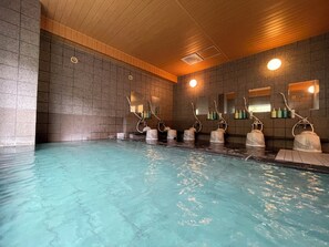 Piscina com vários chuveiros e espelhos na parede.